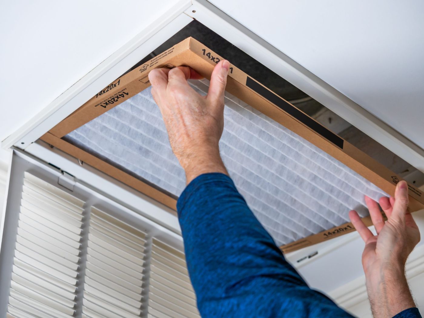 Man installing ceiling air filter in HVAC unit mounted on ceiling
