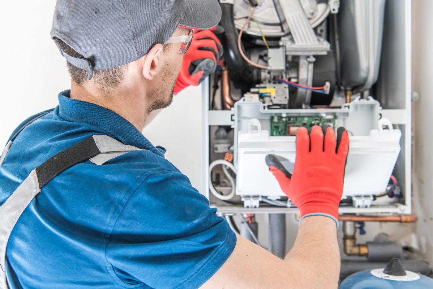 Technician in red gloves servicing HVAC system interior components